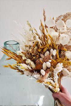 a hand holding a bouquet of dried flowers