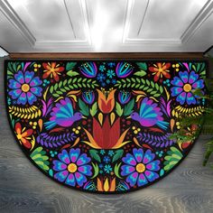 a colorful door mat with flowers and leaves painted on the front, in an entry way