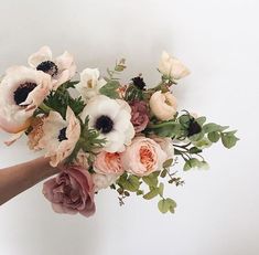 a bouquet of flowers is being held by someone's hand on a white background