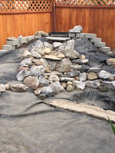 an outdoor area with rocks and gravel in the middle, surrounded by wooden fences