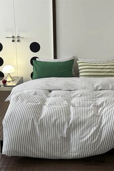 a bed with white and green pillows on top of it next to a night stand