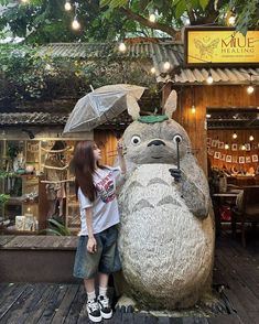 a woman standing next to a large statue of a rabbit holding an umbrella in front of a store