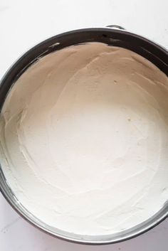 a cake pan filled with white frosting on top of a table