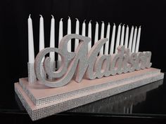 a cake that has candles on it with the word madison spelled in silver glitter letters