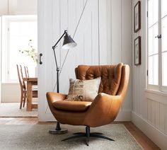 a brown leather chair sitting on top of a rug next to a lamp and table