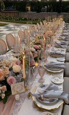 a long table is set with place settings and flowers