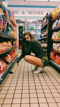 a woman squatting down in the aisle of a grocery store with her legs crossed