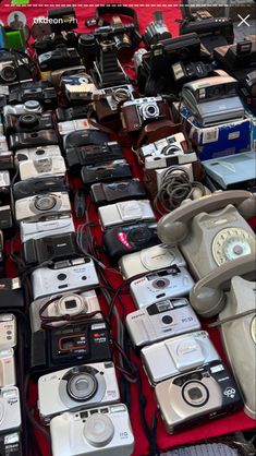 many different types of cameras on display for sale at an outdoor flea market in the city