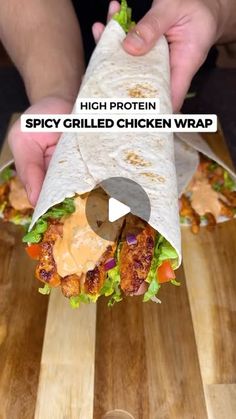 a person holding a burrito on top of a wooden cutting board with the words spicy grilled chicken wrap