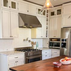 a kitchen with white cabinets and an island in the middle, surrounded by stainless steel appliances