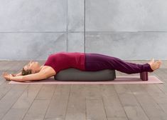 a woman is laying on her stomach while doing a yoga pose in front of a concrete wall