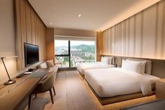 a hotel room with two beds and a desk in front of a large flat screen tv