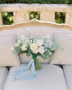 a bouquet of white flowers sitting on top of a couch with blue ribbon around it