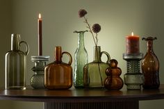 there are many vases and candles on the table