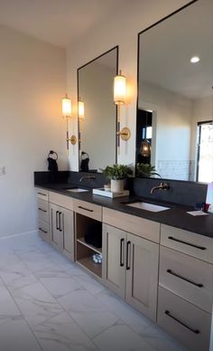 a bathroom with double sinks, mirrors and lights on the wall in it's center