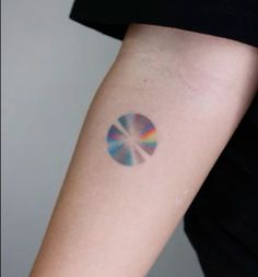 a woman's arm with a colorful disc tattoo on it