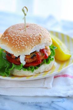 a burger with lettuce, tomato and cheese on it sitting on a plate