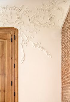 an empty room with a wooden door and brick wall in front of the white painted ceiling