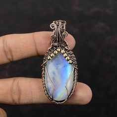 Note : Due to the natural formation of this gemstone. Slight variation in design and color are to be expected.  Rainbow Moonstone Pendant Copper Wire Wrapped Gemstone Pendant Handmade Pendant Moonstone Copper Jewelry Engagement Gift Unique Wire Jewelry Handmade Copper Pendant SKU : VFWP-1452 Gemstone : Rainbow Moonstone Stone Shape : Oval    Metal Purity : Copper Pendant Length : 63 MM   Pendant Width : 27 MM A natural Moonstone opens the Heart Chakra in the human body that helps increase the psychic abilities. Moonstone the emotional healer: A Natural Moonstone encourages feelings of power and natural stability. It balances your emotions and makes the wearer feel confident in any situation. Handmade White Moonstone Gemstones, Nature-inspired Moonstone Jewelry With Natural Stones, Round Moonstone For Jewelry Making, Round Moonstone Gemstones For Jewelry Making, Unique Moonstone Jewelry With Stones, Handmade Moonstone Healing Jewelry, Spiritual Moonstone Pendant Gemstone, Nature-inspired Moonstone Jewelry For Healing, Handmade Tumbled Artisan Jewelry