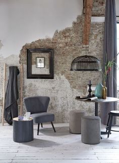 a living room filled with furniture next to a brick wall and a painting on the wall