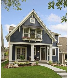 a house with blue siding and white trim on the front door, grass lawn and steps leading up to it