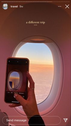 a person holding up a cell phone in front of an airplane window