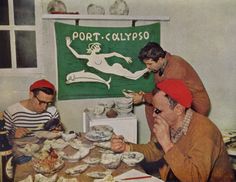 three men sitting at a table with plates of food in front of a sign that reads port - ollippo