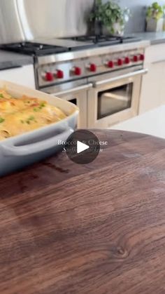 a wooden table topped with a casserole covered in cheese next to an oven