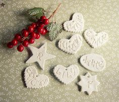 some cookies are sitting on a table next to berries and holly leaves, with the word love spelled in small letters