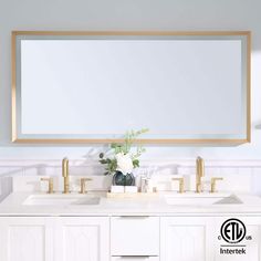 a bathroom vanity with two sinks and a large mirror above it, in front of a white wall