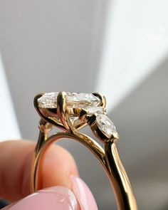 a close up of a person holding a gold ring with three diamonds on it's side