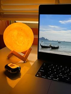 a laptop computer sitting on top of a desk next to a yellow light that is turned on