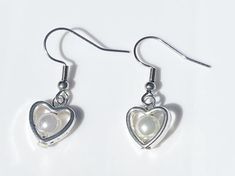 Add some coquette cuteness to your wardrobe with these stylish dangle earrings! Handcrafted from high-quality glass and steel materials, these unique earrings are the perfect whimsical everyday pair! With their complimentary colours and simple silver heart design, these earrings are perfect for adding a fun and trendy twist to any outfit.   Hooks are made from surgical steel, and are suitable for most sensitive ears. Lengths of earrings may vary within pairs. Domestic/Australian Standard shippin Silver Pearl Earrings For Valentine's Day, White Metal Earrings For Valentine's Day, Silver Heart-shaped Pearl Earrings For Gift, Valentine's Day White Metal Earrings, Trendy White Heart Earrings For Gift, Trendy White Heart Earrings Gift, White Metal Heart Earrings, Pierced, Cute Heart-shaped Metal Earrings, White Metal Heart Earrings