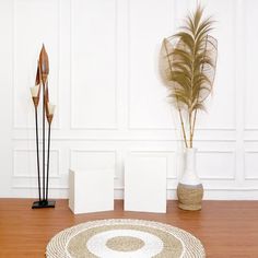 a white vase sitting on top of a wooden floor next to two tall planters