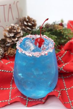 a blue drink sitting on top of a table next to pine cones and christmas decorations