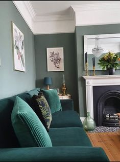 a living room filled with green couches and a fire place in front of a fireplace