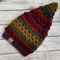 a multicolored knitted beanie hat sitting on top of a wooden table