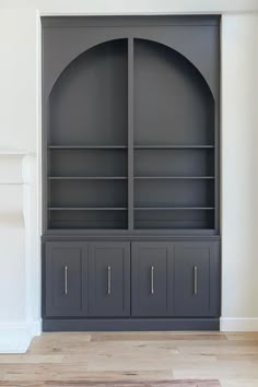 an empty living room with a fireplace and built in bookcases