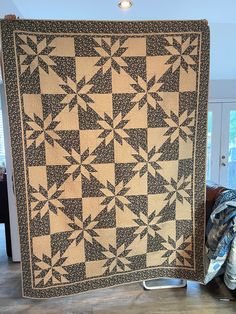 a black and white quilt sitting on top of a wooden floor next to a chair