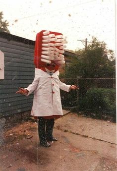 a person in a white coat and red hat is holding up a bunch of doughnuts on their head