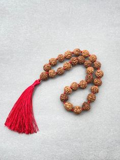 Beads In Mala - Rudraksha Necklace Length - 10-12 Inches Handmade Tassel - 2 Inches Beads Size - 8mm Healing with Rudraksha ♥ Unconditional love ♥ Self-love ♥ Mother love ♥ Caring ♥ Kindness ♥ Friendship ♥ Romantic love ♥ Platonic love Rudraksha is very rare and shastras say this is a highly auspicious one. The ruling deity is Shiva and the ruling planet is sun. This rudraksha is an expensive one available in two types namely round and moon shaped. The wearer of a one mukhi rudraksha is not only blessed by Shiva, but also by Mahalakshmi. This rudraksha enhances the powers of the mind like concentration and confidence. Those who wish to escape bad habits and addictions can depend on this bead. This rudraksha can cure diseases related to the digestive, respiratory and urinary systems in addi Festival Mala With Large Round Beads, Large Beaded Mala For Gifts And Festivals, Hand-strung Mala With Round Beads As Gift, Hand-strung Mala Beads As Gift, Hand-strung Round Beads Mala As Gift, Adjustable Mala With 8mm Beads For Puja, 8mm Round Beads For Festivals, Festive Spiritual Beaded Necklaces, Red Round Beads Mala For Meditation