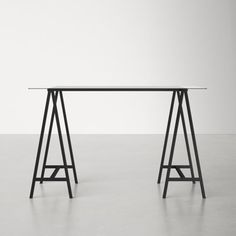 a white table with two black legs and a gray wall in the backgroud