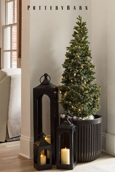 a small christmas tree sitting next to two lanterns