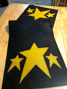 a black and yellow table runner with stars on the top is sitting on a wooden table