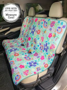 a car seat cover with flowers on it in the back of a vehicle, and one size fits most