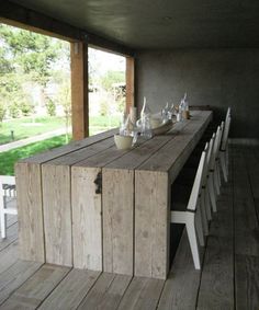 a long table with white chairs and bottles on it in the middle of a room