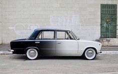 an old black and white car parked in front of a building