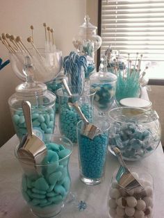 a table topped with lots of candy and candies on top of glass containers next to a window