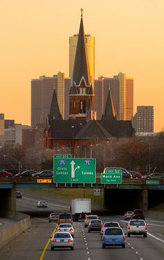 cars driving down the highway in front of a city skyline