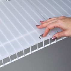 a woman's hand on the edge of a white shelf with nails sticking out of it